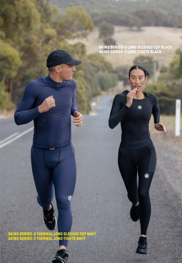 Two athletes running down the road wearing full SKINS compression kit