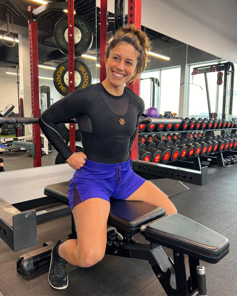 Leah models the SKINS Compression SERIES-5 long sleeve top while lifting in the gym.